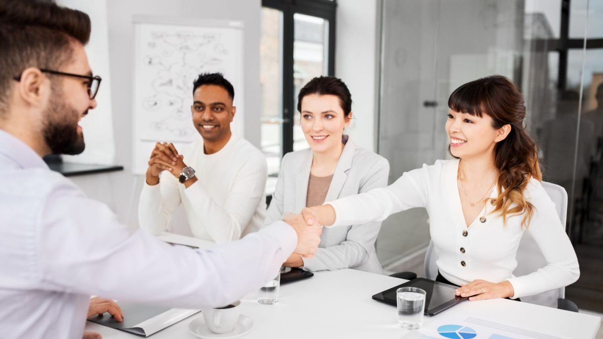 Three interviewers and one candidate. One interviewer is shaking hands with the candidate. This image is for a blog that discusses tips for sales recruiters in Sydney in hiring candidates